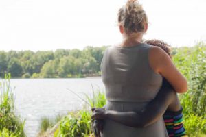 parent and child hugging and looking over water